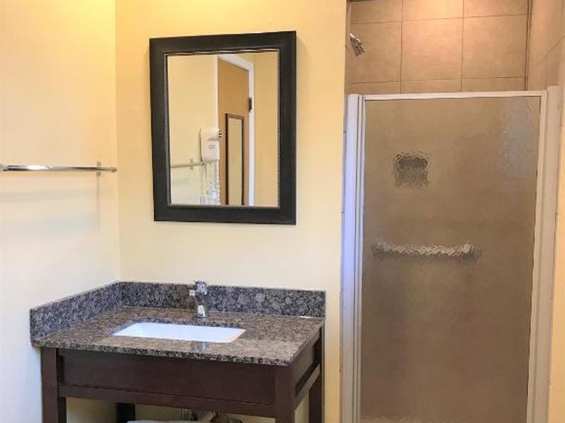 Bathroom with granite vanity, framed mirror, and a walk-in shower