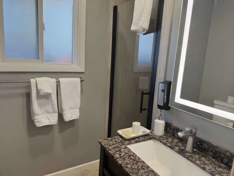 Renovated bathroom with granite vanity, lighted mirror, and fresh towels