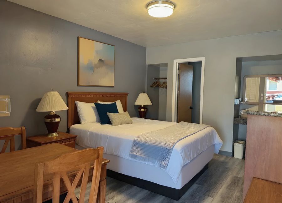 Cozy Queen room with queen bed, table and chairs, and warm bedside lamps